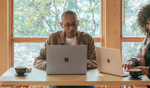 Two people working on computers in a well lit room.