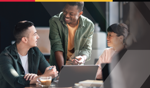 Three people chat while working around a laptop.
