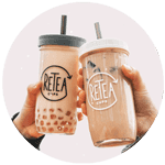 Two hands holding reusable RETEA cups filled with bubble tea, featuring eco-friendly lids and metal straws against a soft pastel background.