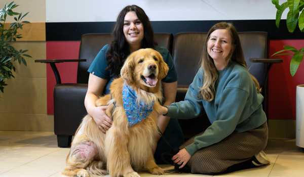 Two PetTrust students petting a Golden Retriever