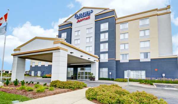 Exterior view of Fairfield Inn & Suites by Marriott Guelph, featuring the hotel entrance with well-maintained landscaping and a Canadian flag.