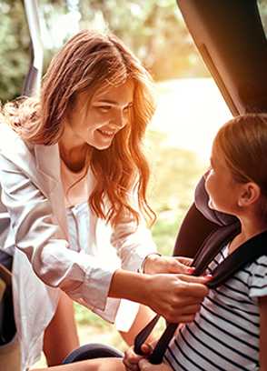 A mother buckles a child's car seat.